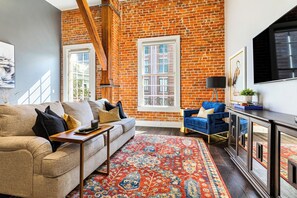 Open-concept living, kitchen, and dining area with ample seating. 65” Samsung Smart 4K TV with streaming and DIRECTV Entertainment. Sofa converts to a queen sleeper. Dining table seats four. Enjoy plenty of natural light!