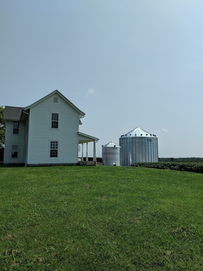 View of the house from the road with grain bins in the background