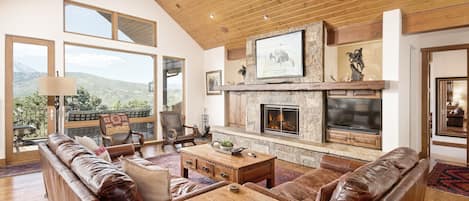 Main floor living space with wood-burning fireplace, TV, views of Mt. Sopris, and access to your main deck