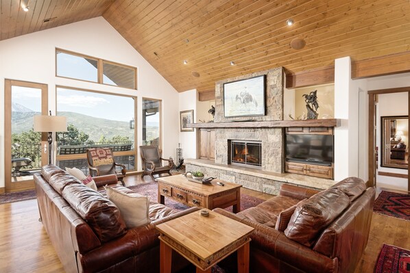 Main floor living space with wood-burning fireplace, TV, views of Mt. Sopris, and access to your main deck