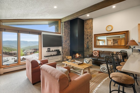 The living room features a flat screen TV, wood burning fireplace and access to the balcony with a gas grill.