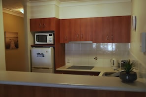 Kitchen with fridge, microwave and touchpad ceramic hotplates.