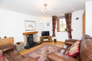 Living room with log burning stove and window to front