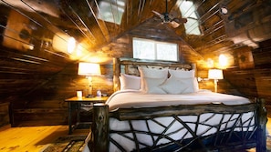 The loft bedroom features a plush king-sized bed with log frame.