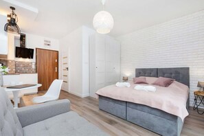 A multifunctional space where the living room flows into the sleeping area. A comfortable bed and a small sofa provide versatility, while warm lighting creates an inviting atmosphere.