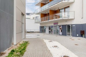 The entrance to a contemporary residential building, featuring sleek architecture, well-maintained walkways, and an urban setting.