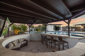 Resort style yard with lazy river pool, spa, putting green, BBQ grill, swim up bar, smart TV, covered patio, outdoor dining area, and MORE!