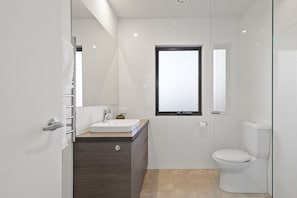 Clean bathroom with shower, wooden cabinet design and soft towels.