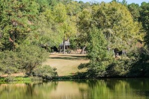 The cottage from across the private, spring-fed pond--one of two guests may enjoy accessing via .5 mile walking trail loop. Contact hosts to complete waiver for swimming or boating.