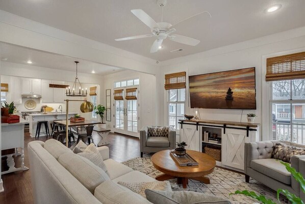 The living area has plush comfortable seating, a 63-inch HDTV with cable and Netflix, and plenty of warm lighting for you to pull down the custom bamboo blinds, cozy on up, and hop in a book. Post-picture additions: A sound system and subwoofer. 