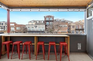 Step outside & enjoy the perfect perspective of Dickson Street! With views of University of Arkansas' Old Main in the distance! Your own private patio features a covered balcony with string lights and custom wooden top + 6 Razorback red bar stools.
