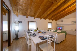 The living room with dinner table, sofabed and TV