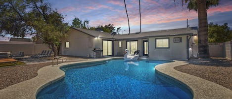 Private Backyard Oasis featuring a sparkling blue pool, sun loungers, covered patio, firepit with outdoor furnishing.