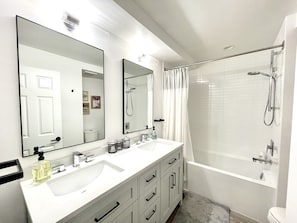 Bathroom with double vanity, and a tub and shower combo.