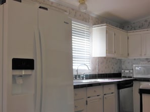 L-shaped kitchen shows refrigerator, dishwasher & MW.  Stove is in island.