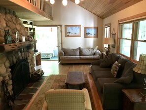 High-ceiling living room with stone fireplace.  Sleeper sofa.