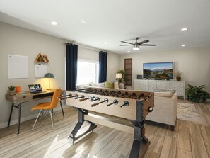 Open concept living area with Smart TV, dedicated work station, foosball, and designer funishings.