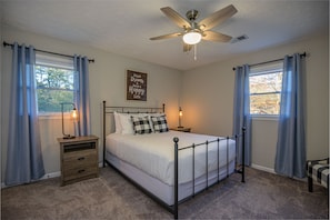 Guest bedroom has a queen size bed and ceiling fan.