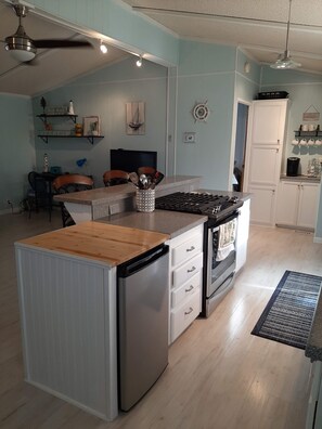 Kitchen has slide-in gas stove and mini fridge.