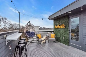 There is a large green wall with light up Nashville sign, hanging lights, and even a bar and bar stools to hang out and have a cocktail and take in the Downtown Views