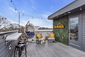 This home boasts an amazing private rooftop with downtown views and plenty of space to spread out and relax.
There is a large green wall with light up Nashville sign, hanging lights, and even a bar and bar stools to hang out and have a cocktail and take in the Downtown Views