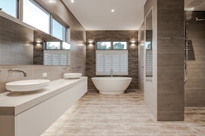 The ground-floor family bathroom features a large tub, walk-in rain shower, and twin vanities for shared comfort.