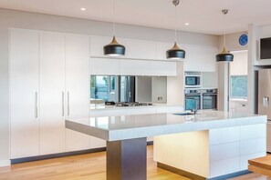 The main kitchen is fully equipped with twin ovens, 900mm gas cooktop, microwave, and sleek marble island.