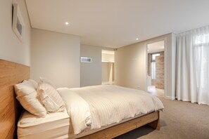 The primary bedroom features a queen bed, plush furnishings, and access to a luxurious ensuite and walk-in wardrobe.