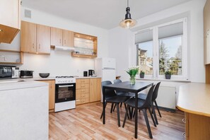 A kitchen and dining area with wooden cabinets, a black countertop, and a small dining table with four chairs. 
