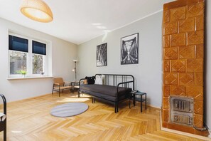 A combined living and bedroom area featuring a black sofa, metal-frame bed, small round rug, and wall art. 
