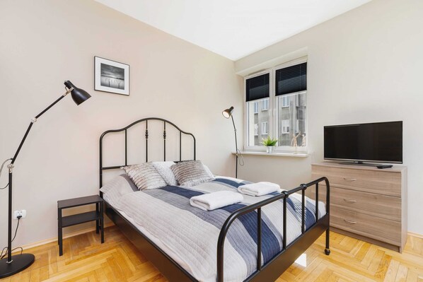 Studio with comfortable and stylish double bed, television for evening relax, elegant lamp, and capacious cabinet.