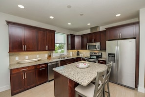 spacious kitchen with granite counter, granite island that seats two and wide plank wood tile flooring.  All dishes, pots and pans are provided.