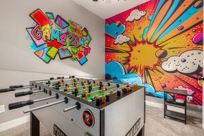 Game room featuring tournament-grade foosball table and commercial video arcade game.