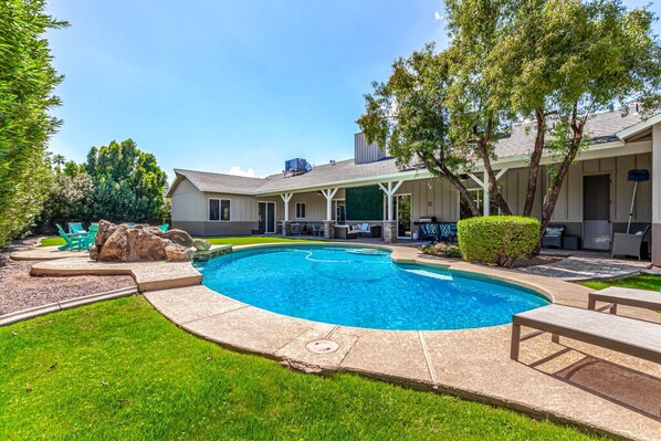 Backyard with covered patio, multiple seating areas, ping pong table, yard games, BBQ grill, fire pit, sun loungers, and sparkling pool.