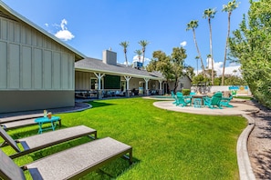 Backyard with covered patio, multiple seating areas, ping pong table, yard games, BBQ grill, fire pit, sun loungers, and sparkling pool.