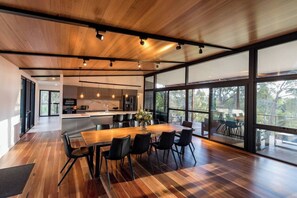 Gather for meals and conversation at the long timber table, where treetop views and soft natural light set the perfect atmosphere.