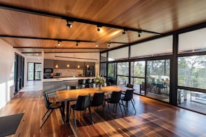 Gather for meals and conversation at the long timber table, where treetop views and soft natural light set the perfect atmosphere.
