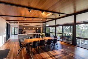 Gather for meals and conversation at the long timber table, where treetop views and soft natural light set the perfect atmosphere.