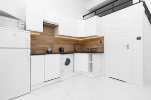 A modern white kitchen with wooden countertops, minimalistic cabinets, and built-in appliances.
