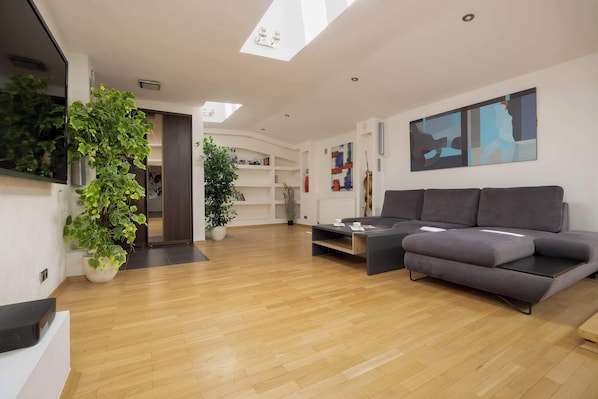 A modern living room with a grey sectional sofa, wooden floors, and wall art creating a relaxed, stylish ambiance.
