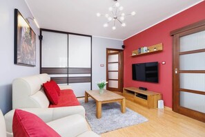Another view of the same living room, emphasizing the sofa, coffee table, and a large flat-screen TV mounted on the wall.