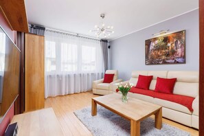  A slightly different angle of the living room, showing the open layout with the sofa, a wooden coffee table, and curtains framing the large windows.