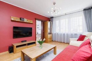 Another view of the same living room, emphasizing the sofa, coffee table, and a large flat-screen TV mounted on the wall.