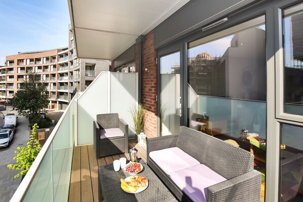South facing balcony with seating and city views