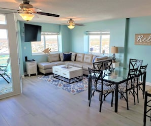 Living area with natural light abounding, leather sectional & dining table for 6