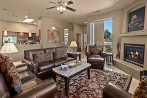 Comfy leather couches surround a gas fireplace and flat screen TV