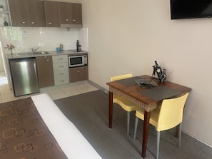 Kitchenette, fridge, cooktop, microwave, dining table.