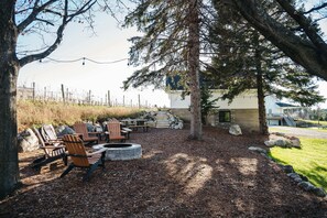 Comfy adirondack seating around the fire pit surrounded by a pocket of pine trees