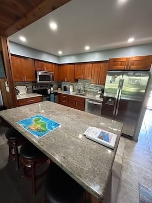 Large granite counter top Island  in kitchen with 4 swivel  bar stools