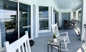 A spacious balcony with outdoor rocking and dining chairs. 208 1140 Ocean Blvd, Isle of Palms, SC | IOP Escapes